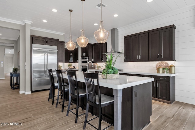 1145 E Gleneagle Dr, Chandler, AZ 85249 - kitchen with stainless steel appliances, wall chimney exhaust hood, ornamental molding, recessed lighting, and light wood-style flooring