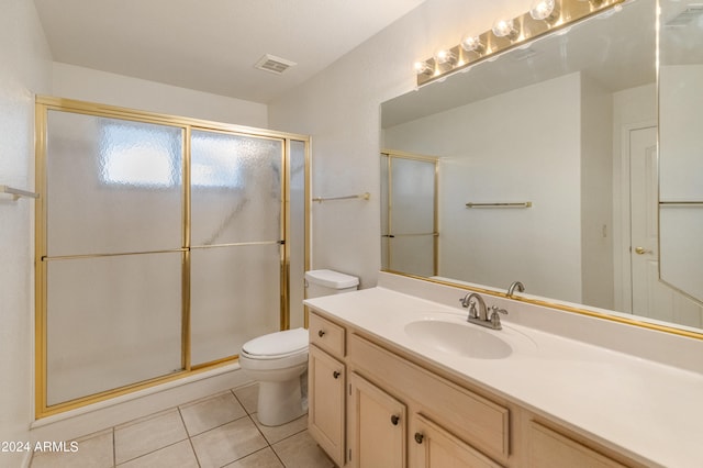 bathroom with toilet, tile patterned flooring, vanity, and a shower with door