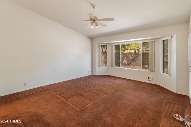 spare room featuring ceiling fan and dark colored carpet