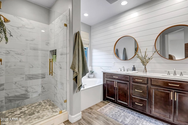 full bathroom featuring a garden tub, wood finished floors, a sink, and a stall shower