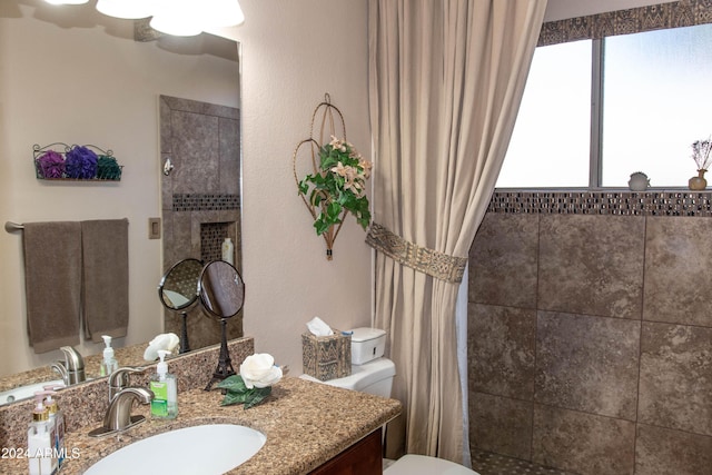 full bathroom with toilet, vanity, tiled shower, and a tile fireplace