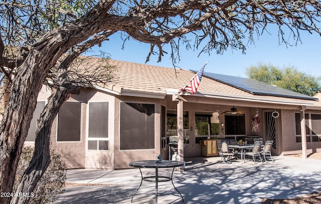 rear view of property with a patio, solar panels, and stucco siding