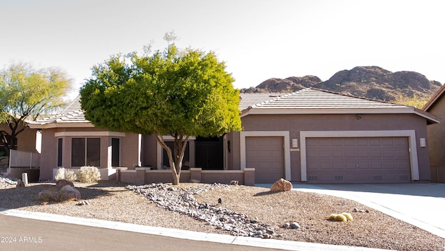 view of front of home featuring a garage, driveway, a tiled roof, a mountain view, and stucco siding