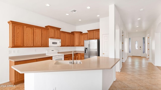 kitchen with white appliances, light tile patterned floors, sink, and a large island