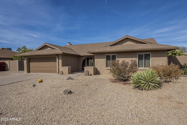 ranch-style house with a garage, concrete driveway, roof with shingles, fence, and brick siding