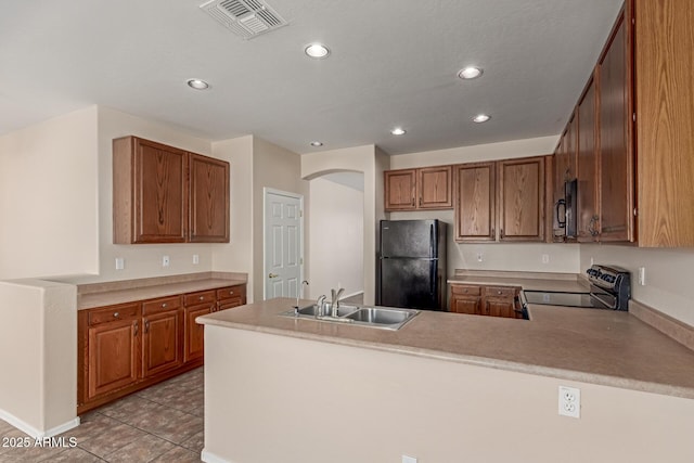 kitchen featuring visible vents, black appliances, a sink, arched walkways, and a peninsula