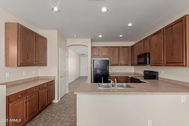 kitchen with recessed lighting, a peninsula, arched walkways, black appliances, and a sink