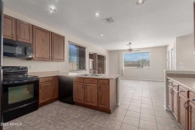 kitchen with visible vents, light countertops, a peninsula, black appliances, and a sink