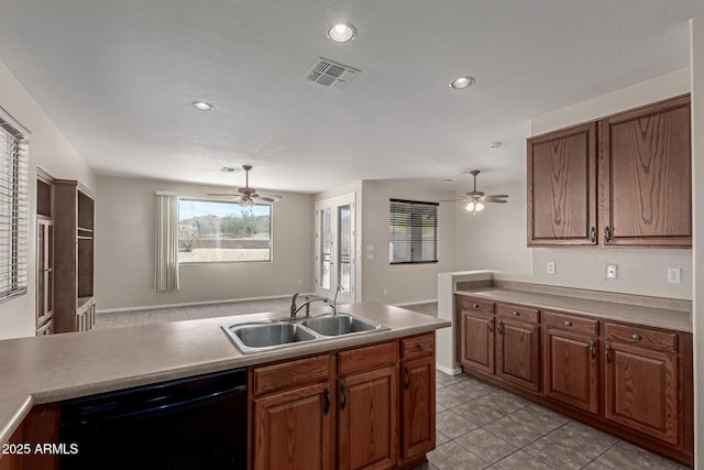 kitchen with brown cabinetry, visible vents, light tile patterned flooring, a sink, and black dishwasher