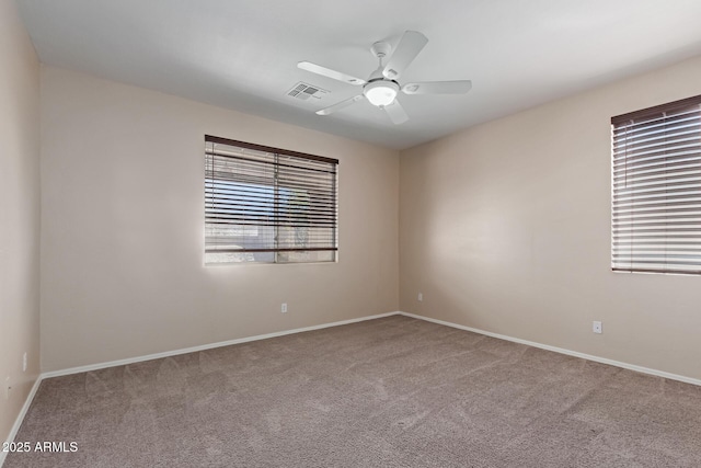 carpeted spare room featuring visible vents, baseboards, and ceiling fan