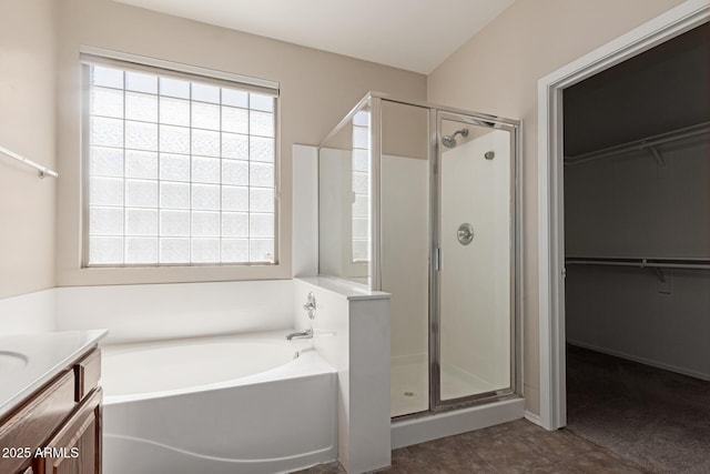 bathroom featuring vanity, a spacious closet, a bath, and a shower stall