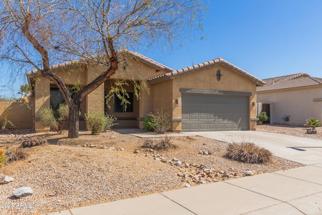 mediterranean / spanish home with stucco siding, a tiled roof, concrete driveway, and a garage