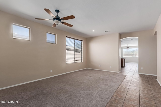 carpeted spare room with plenty of natural light, visible vents, arched walkways, and baseboards