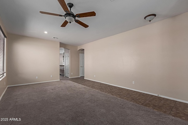 unfurnished room featuring dark colored carpet, visible vents, arched walkways, and baseboards