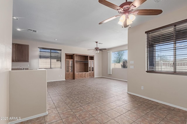 unfurnished living room with light tile patterned floors, baseboards, visible vents, a sink, and ceiling fan