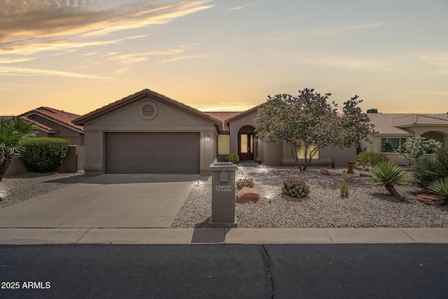 view of front of property featuring a garage, driveway, stucco siding, and a tiled roof