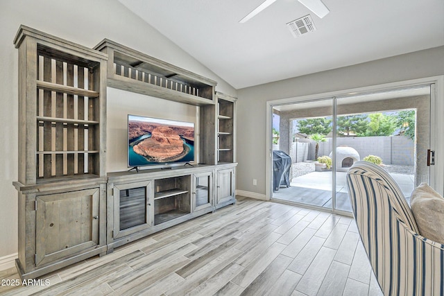 living room with lofted ceiling, light wood-style flooring, ceiling fan, and baseboards