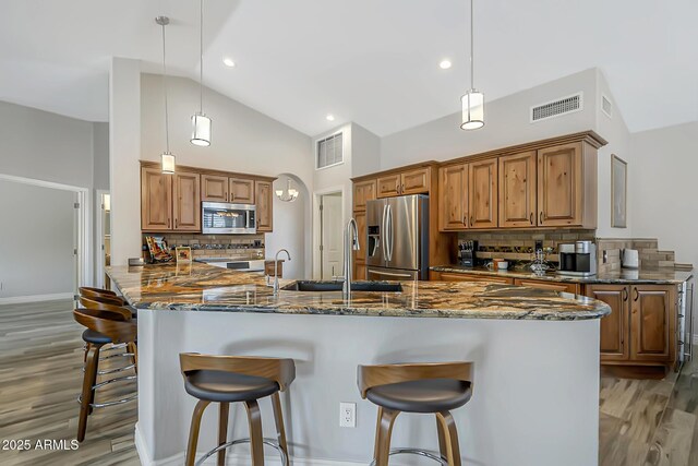 kitchen with appliances with stainless steel finishes, a sink, light wood-style flooring, tasteful backsplash, and recessed lighting