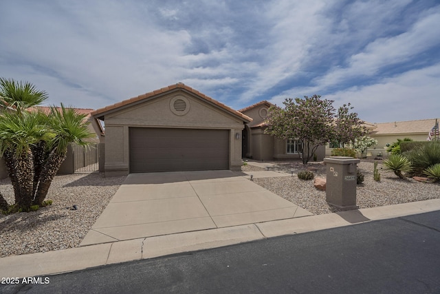 view of front of home with driveway, stucco siding, a tiled roof, and an attached garage