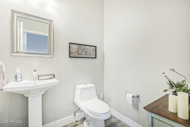 bathroom with baseboards, toilet, and wood finished floors