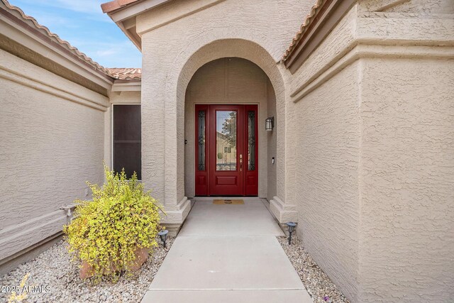 entrance to property with stucco siding and a tiled roof