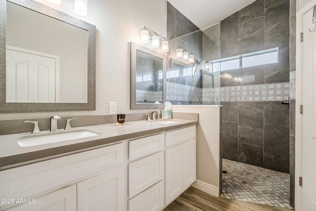 full bath with walk in shower, double vanity, and wood finished floors