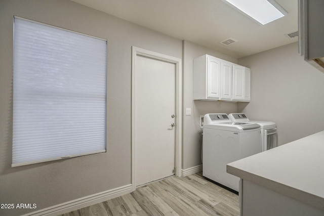 washroom featuring cabinet space, separate washer and dryer, light wood finished floors, and baseboards