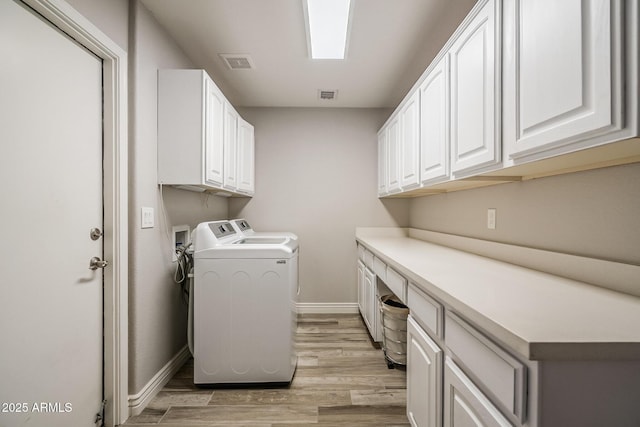 washroom with cabinet space, light wood-type flooring, washer and dryer, and baseboards