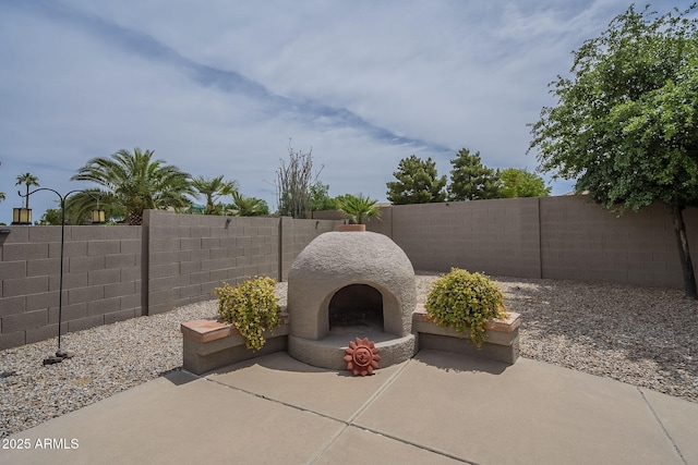view of patio featuring a fenced backyard and exterior fireplace
