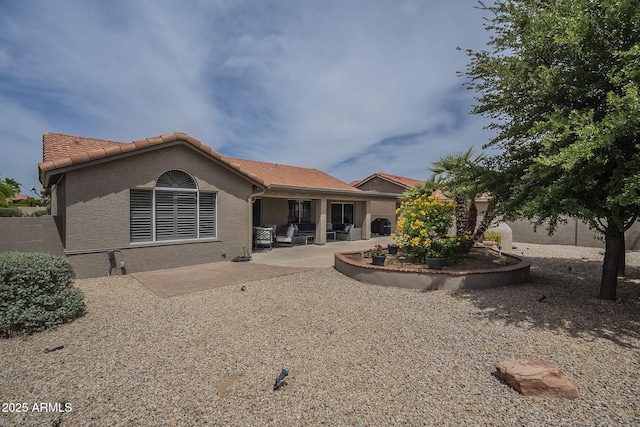 rear view of property featuring fence, a patio area, stucco siding, and a tiled roof