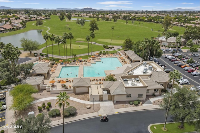 aerial perspective of suburban area with a golf course, a pool, and a water and mountain view