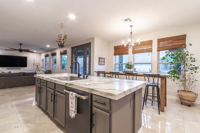 kitchen with a sink, visible vents, hanging light fixtures, gray cabinets, and dishwasher