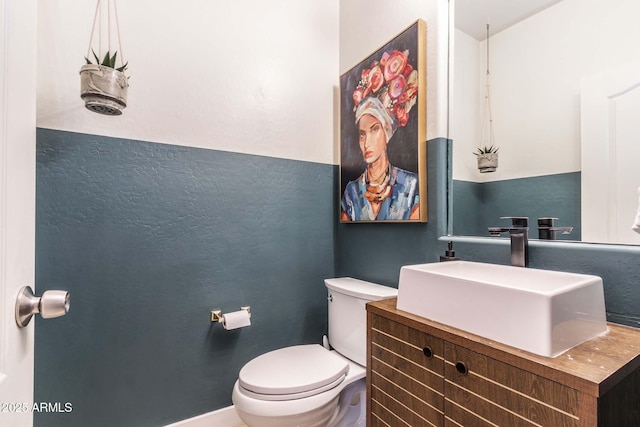 bathroom with vanity, toilet, and baseboards