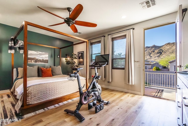 bedroom featuring baseboards, visible vents, wood finished floors, access to exterior, and a mountain view