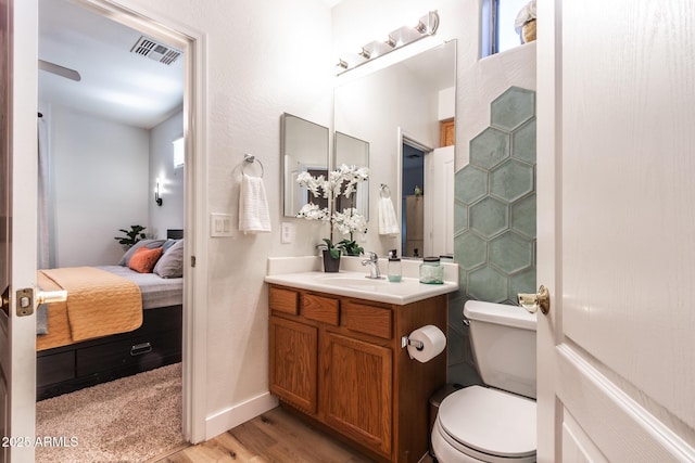 ensuite bathroom featuring visible vents, toilet, connected bathroom, vanity, and wood finished floors