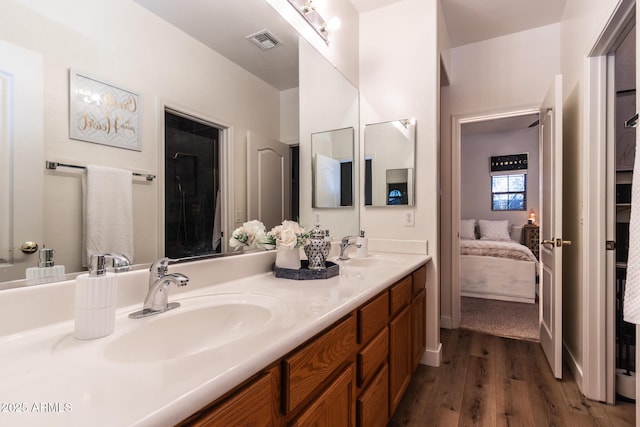 ensuite bathroom with connected bathroom, visible vents, a sink, and wood finished floors