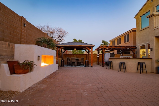 view of patio / terrace featuring a fenced backyard, outdoor dry bar, a gazebo, and a pergola