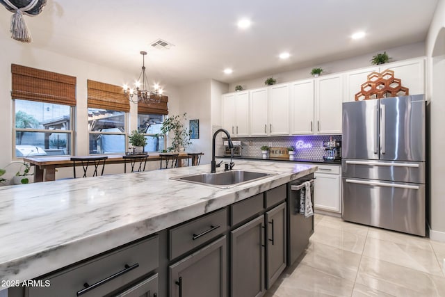 kitchen with appliances with stainless steel finishes, white cabinets, visible vents, and a sink