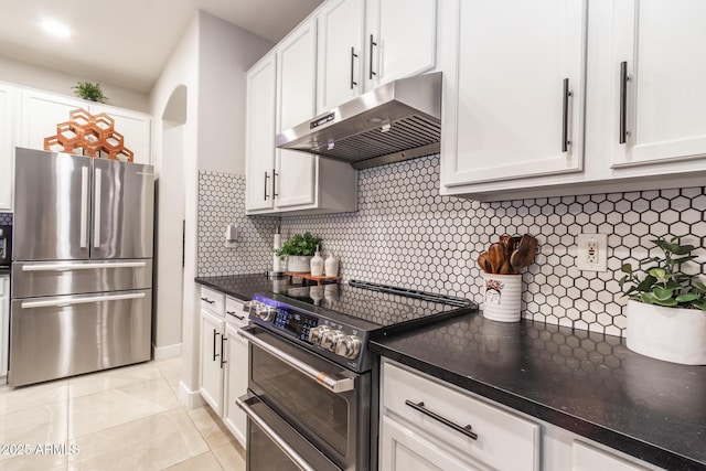 kitchen with exhaust hood, white cabinetry, range with two ovens, and freestanding refrigerator