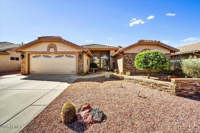 view of front of property with a tile roof, stucco siding, stone siding, driveway, and a garage