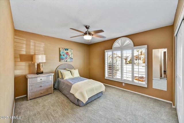 bedroom with baseboards, a closet, ceiling fan, and carpet flooring