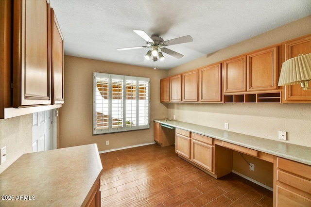 kitchen featuring light countertops, dishwasher, ceiling fan, wood finished floors, and built in study area