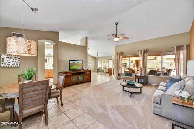 living area featuring visible vents, arched walkways, light tile patterned floors, and a ceiling fan