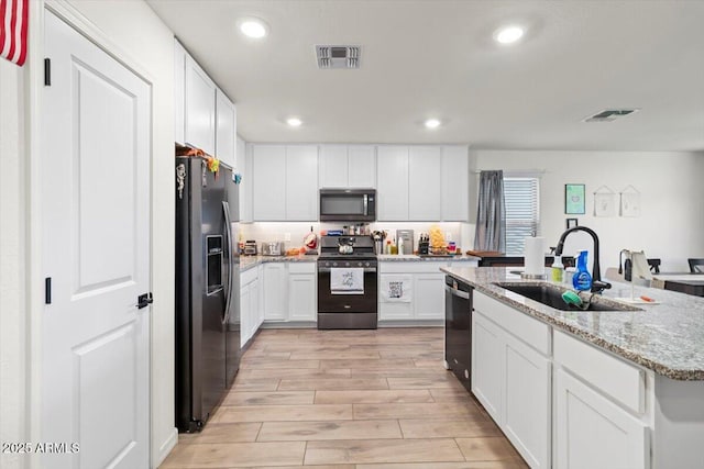 17461 W Molly Ln, Surprise, AZ 85387 - kitchen featuring appliances with stainless steel finishes, a sink, white cabinets, light wood-type flooring, and a center island with sink