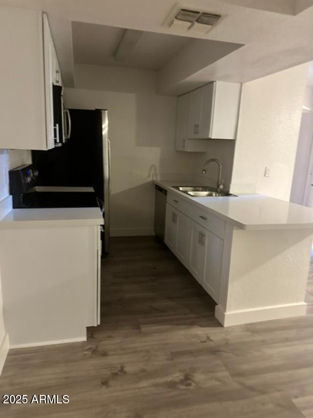 kitchen with white dishwasher, sink, white cabinets, range, and dark hardwood / wood-style floors