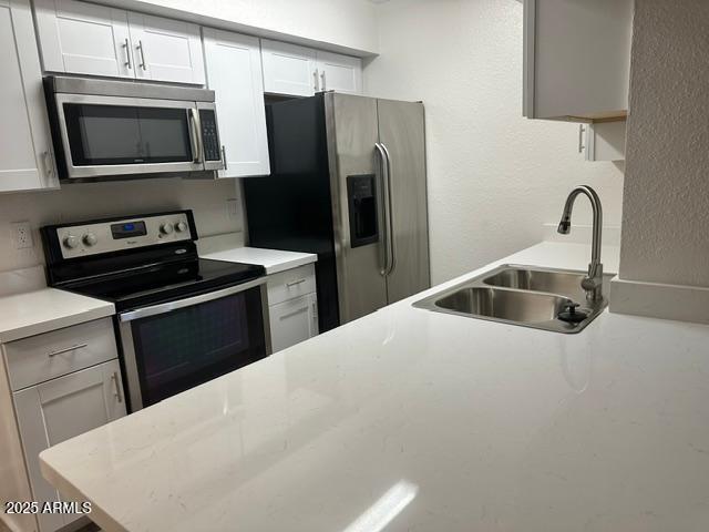 kitchen featuring appliances with stainless steel finishes, white cabinetry, and sink