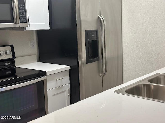 kitchen featuring white cabinetry, sink, and appliances with stainless steel finishes