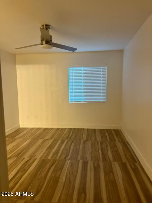 empty room with hardwood / wood-style floors and ceiling fan