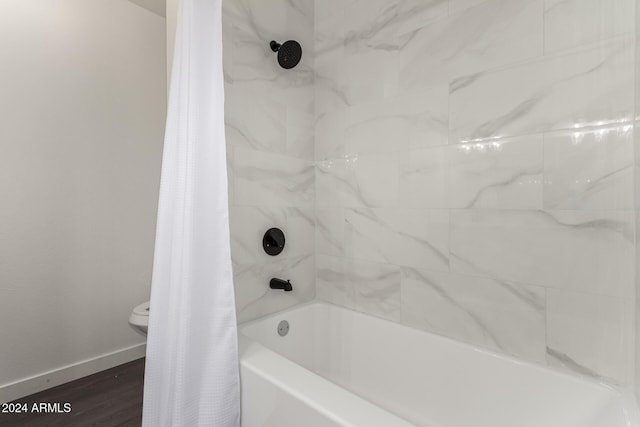 bathroom with wood-type flooring, toilet, and shower / bath combo with shower curtain