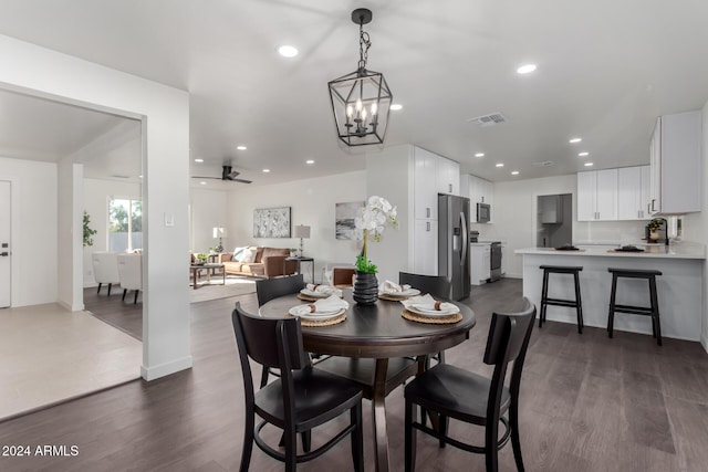 dining space featuring dark hardwood / wood-style flooring and ceiling fan with notable chandelier